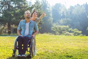 Look there. Pleasant young woman standing behind her incapacitated husband in a wheelchair and pointing at something in the distance