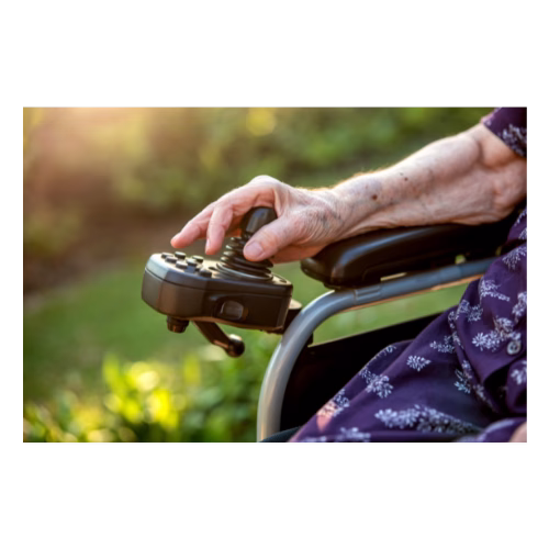 A woman sat in an electric wheelchair with only her arm and a very small part of her lower body is visible. Her hand is on the control panel.