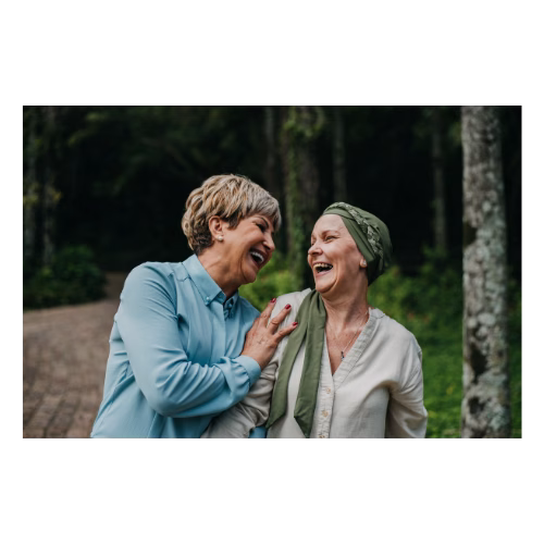 Two women laughing one with a green headscarf on