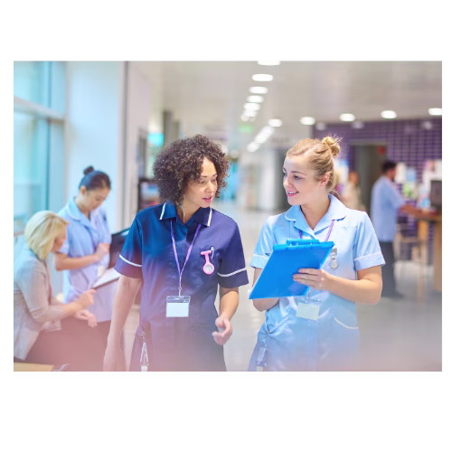 Two nurses with one holding a clipboard that they are both looking at.