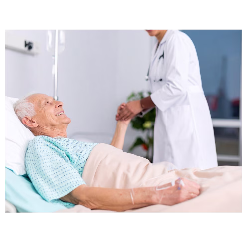 A male patient in a hospital bed with a female doctor holding his hand.